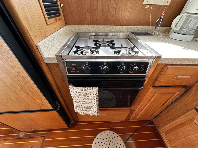 Slide: The Image of 1998 Mainship 350 Trawler kitchen with stove, wooden cabinets, and countertop appliances. - 36
