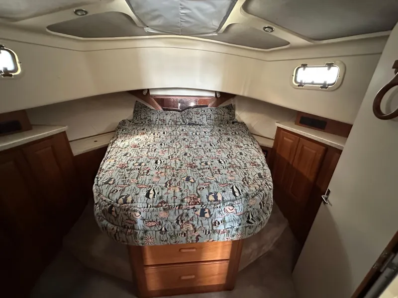 Slide: The Image of 1998 Mainship 350 Trawler cabin with cozy bed, wooden cabinets, and natural light. - 42