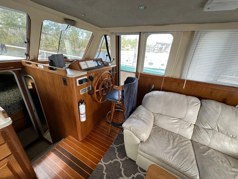 Slide: The Image of Interior of 1998 Mainship 350 Trawler with helm, wooden accents, and beige seating. - 43