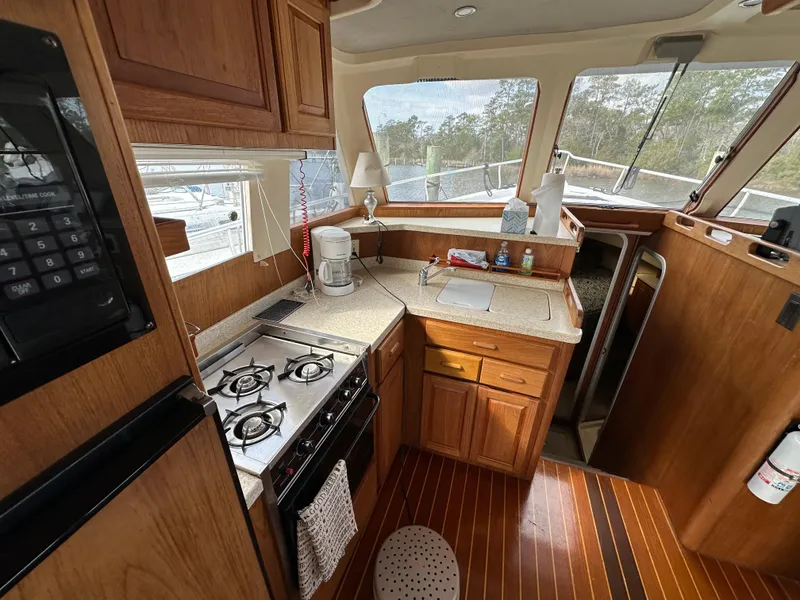 Slide: The Image of 1998 Mainship 350 Trawler kitchen with stove, wooden cabinets, and countertop. - 44