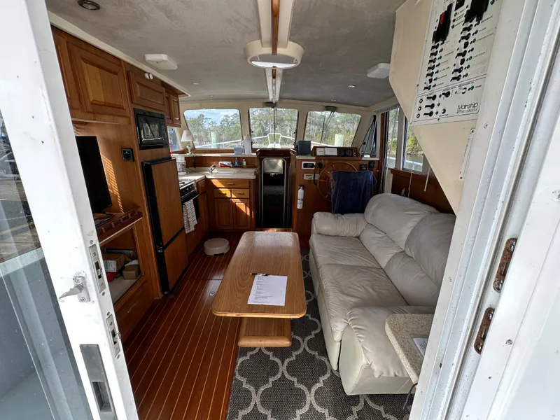 Slide: The Image of 1998 Mainship 350 Trawler interior with sofa, table, and kitchen area. - 48