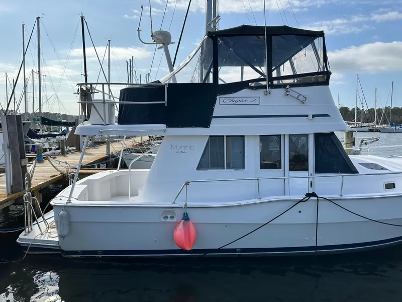 Slide: The Image of 1998 Mainship 350 Trawler docked at marina, featuring upper deck and cabin. - 5