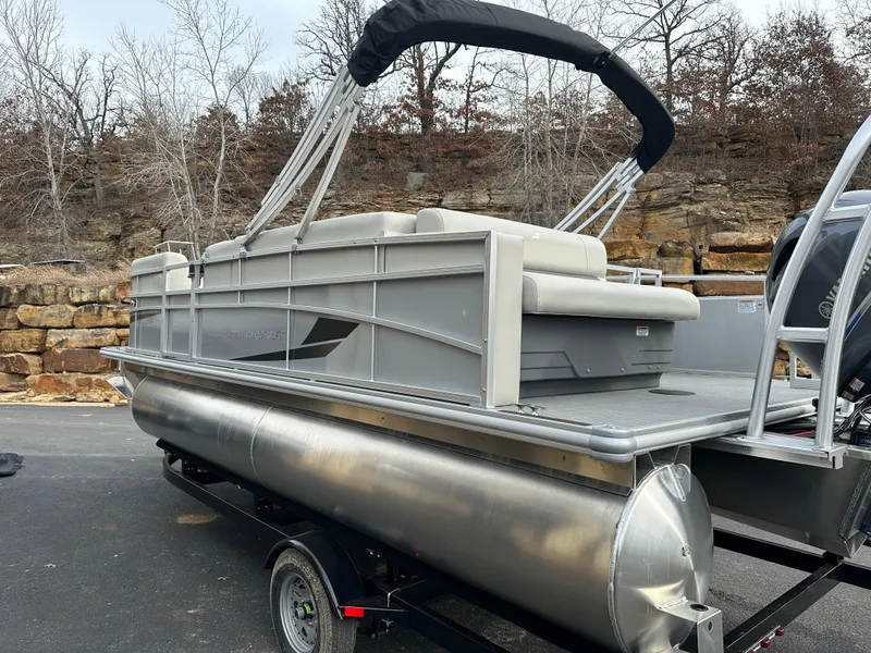 Slide: The Image of 2024 Starcraft LX 20 CB pontoon boat on trailer, parked outdoors. - 2