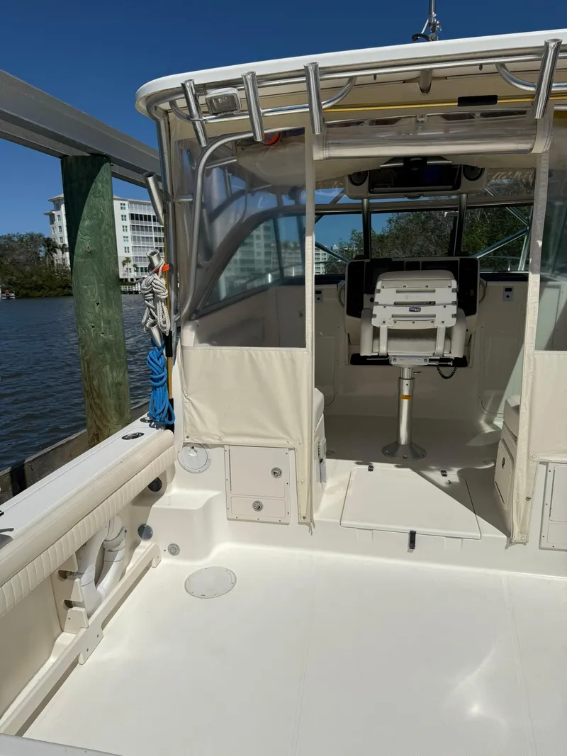 Slide: The Image of 2011 World Cat 320 EC boat interior, featuring helm and seating area, docked by the water. - 16