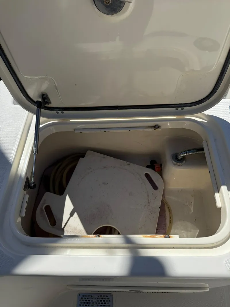 Slide: The Image of Open storage compartment on 2011 World Cat 320 EC boat, containing coiled hose and accessories. - 24