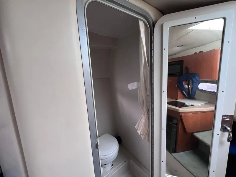 Slide: The Image of Interior of 2002 Four Winns 268 Vista boat, featuring bathroom and kitchenette area. - 27