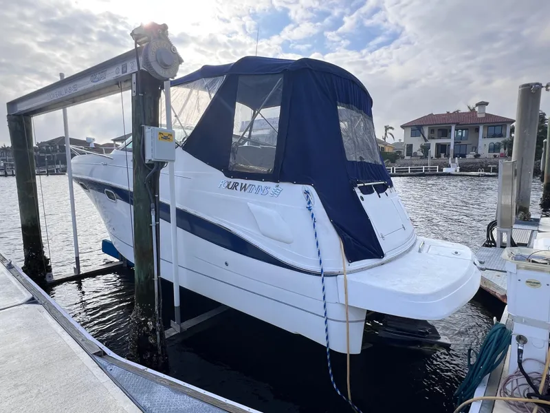 Slide: The Image of Four Winns 268 Vista boat docked, featuring 2023 motor replacement, under a cloudy sky. - 3