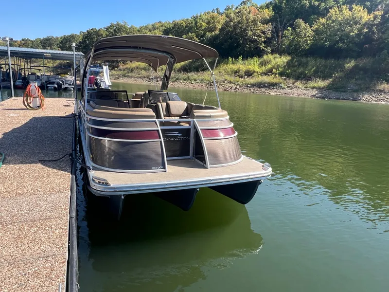 Slide: The Image of 2016 Bennington 2552 QCW I/O pontoon boat docked on a calm lake. - 10