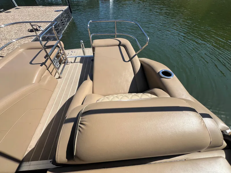 Slide: The Image of 2016 Bennington 2552 QCW I/O boat with tan leather seating and cup holder by the water. - 12