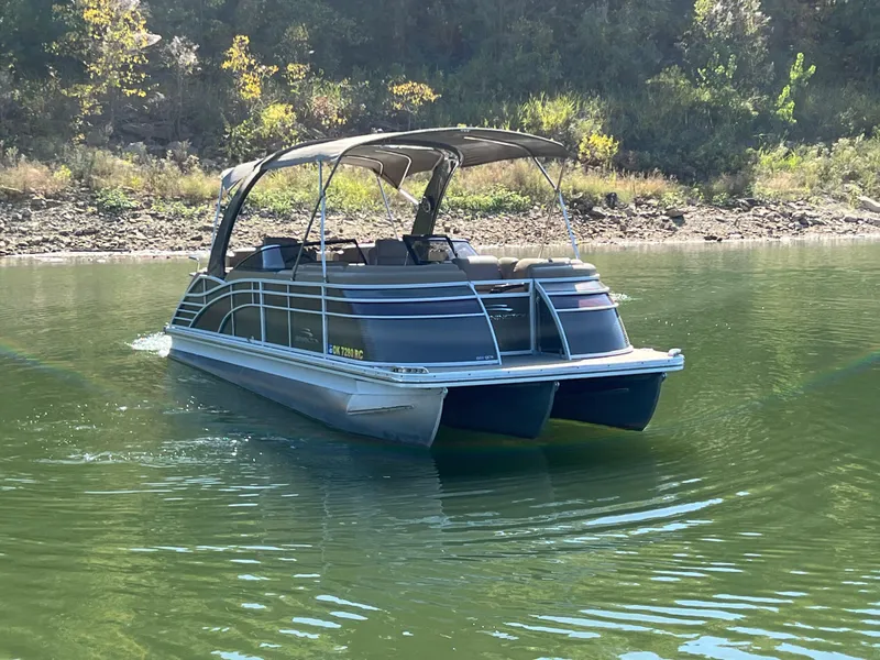 Slide: The Image of 2016 Bennington 2552 QCW I/O pontoon boat on a calm lake. - 2