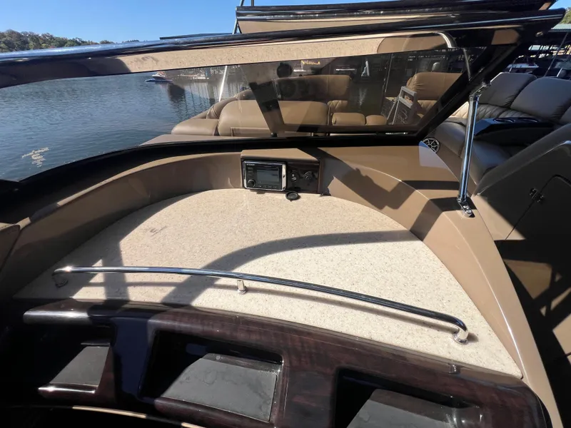 Slide: The Image of 2016 Bennington 2552 QCW I/O boat interior with dashboard and seating, docked by the water. - 24