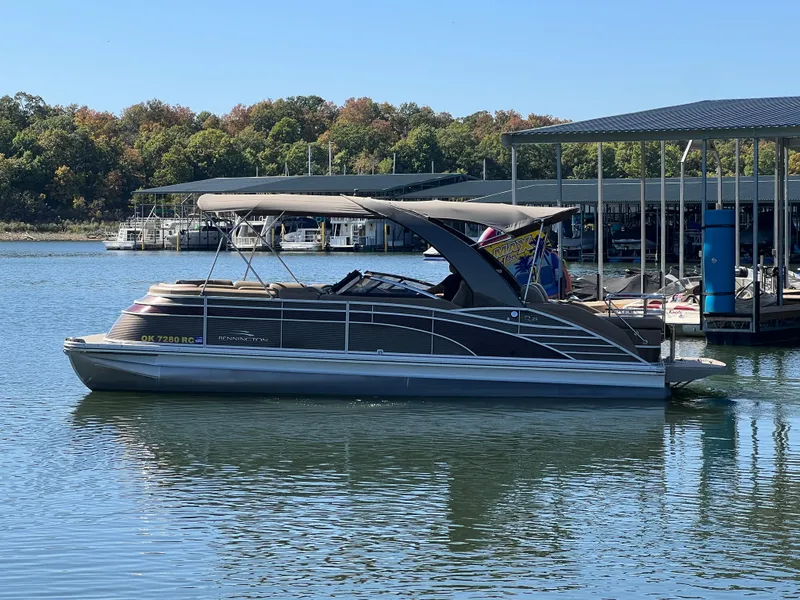 Slide: The Image of 2016 Bennington 2552 QCW I/O pontoon boat docked on a calm lake. - 6