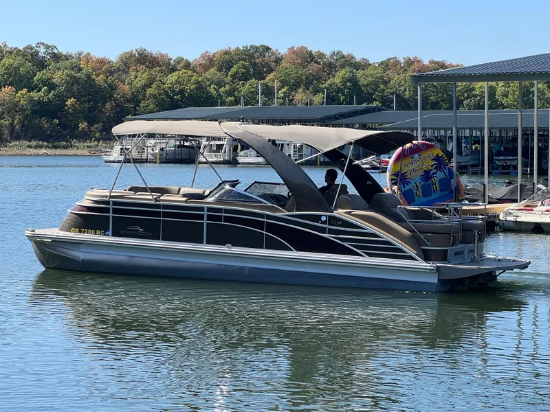 Slide: The Image of 2016 Bennington 2552 QCW I/O pontoon boat on a calm lake near a marina. - 7