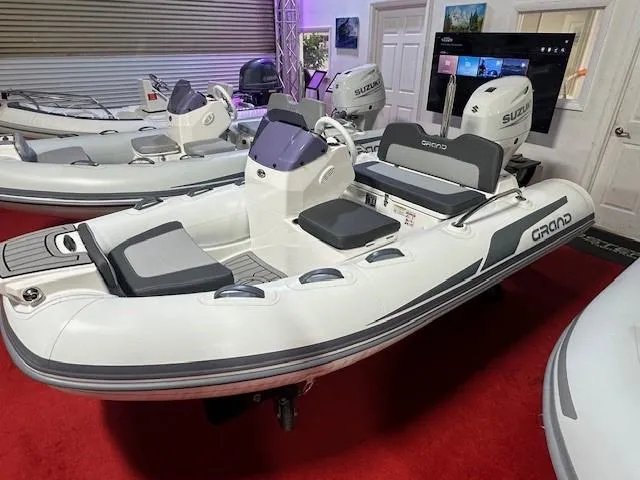 The Image of 2025 Grand Inflatables G340 boat displayed indoors on red carpet. - 0