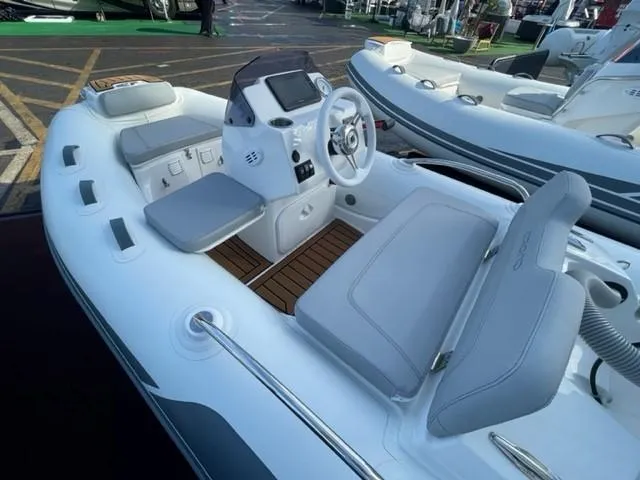 Slide: The Image of 2025 Grand Inflatables G340 boat interior with gray seating and modern dashboard. - 10