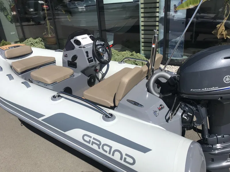 Slide: The Image of 2025 Grand Inflatables G340 boat with Yamaha outboard motor, beige seating, and steering console. - 4