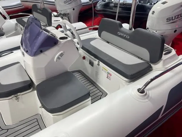 Slide: The Image of 2025 Grand Inflatables G380 boat interior with gray seating and steering console. - 3