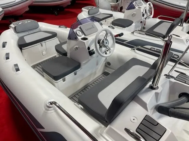 Slide: The Image of 2025 Grand Inflatables G380 boat interior with steering wheel and seating, showcased on red carpet. - 4