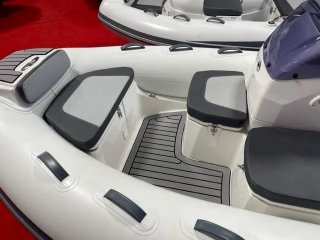 Slide: The Image of 2025 Grand Inflatables G380 boat interior with cushioned seating and sleek design. - 5