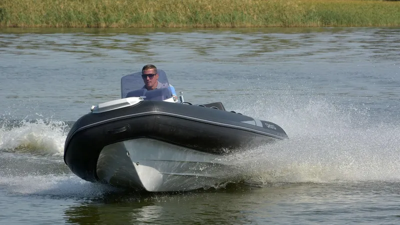 Slide: The Image of 2025 Grand Inflatables G420 boat speeding on water with driver, creating splashes. - 12