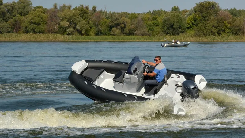 Slide: The Image of 2025 Grand Inflatables G420 boat navigating a lake with a driver, creating waves. - 13