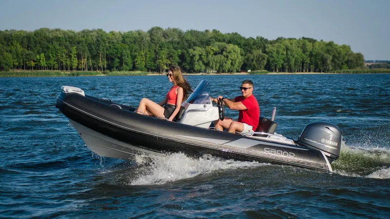 Slide: The Image of 2025 Grand Inflatables G420 boat cruising on a lake with two passengers. - 15