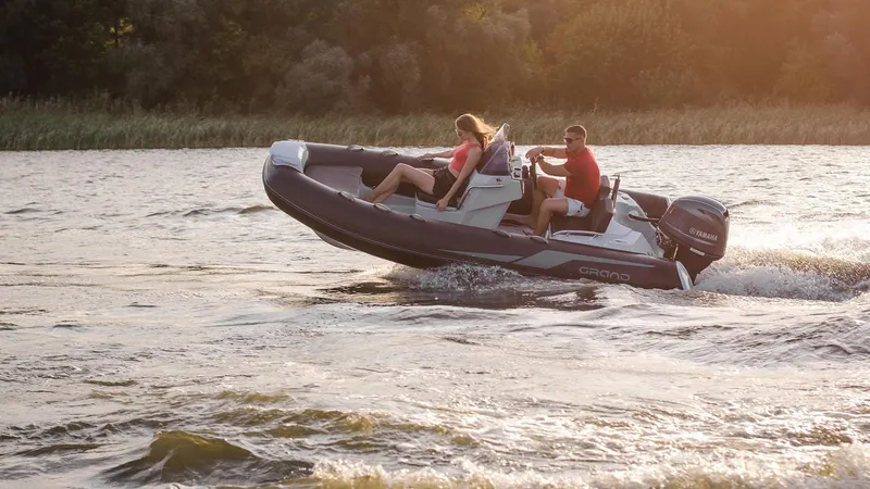 Slide: The Image of 2025 Grand Inflatables G420 boat speeding on a lake at sunset. - 19