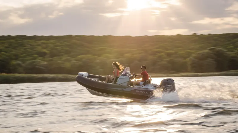 Slide: The Image of 2025 Grand Inflatables G420 boat cruising on a lake at sunset. - 21