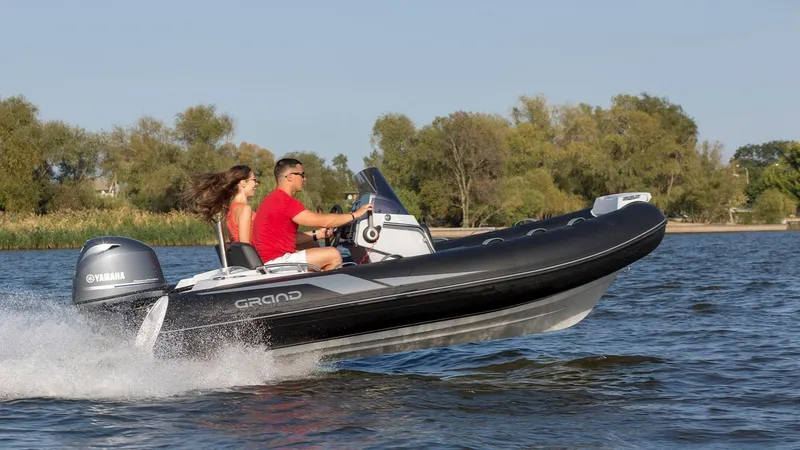 Slide: The Image of 2025 Grand Inflatables G420 boat speeding on water with two passengers, Yamaha engine visible. - 24