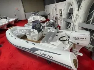Slide: The Image of 2025 Grand Inflatables G420 boat with Suzuki engine on red carpet display. - 4