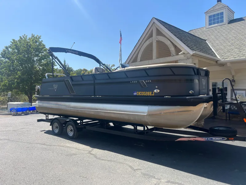 Slide: The Image of 2022 Viaggio Lago S pontoon boat on trailer, parked near a building. - 8