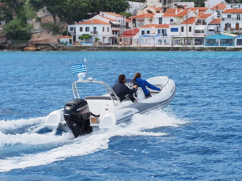 Slide: The Image of 2025 Grand Inflatables G500 boat cruising near coastal village with Greek flag. - 11