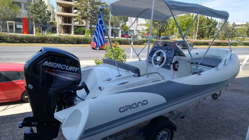 Slide: The Image of 2025 Grand Inflatables G500 boat with Mercury engine, parked on a trailer, featuring a canopy. - 4