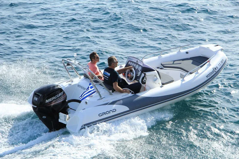 Slide: The Image of 2025 Grand Inflatables G500 boat cruising on open water with two passengers. - 7