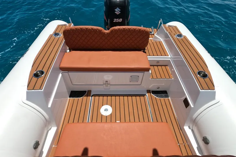 Slide: The Image of 2025 Tiger Marine 740 PL boat interior with teak flooring and cushioned seating, on clear blue water. - 16