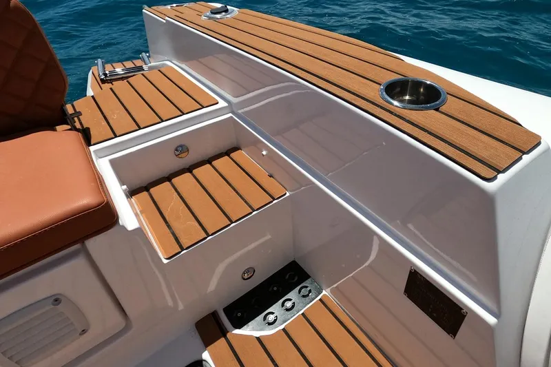 Slide: The Image of 2025 Tiger Marine 740 PL boat deck with wood finish and cup holder on blue water. - 17