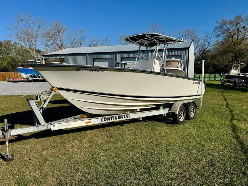 Slide: The Image of 2008 Contender 21 Open boat on trailer, parked on grass near a metal building. - 1
