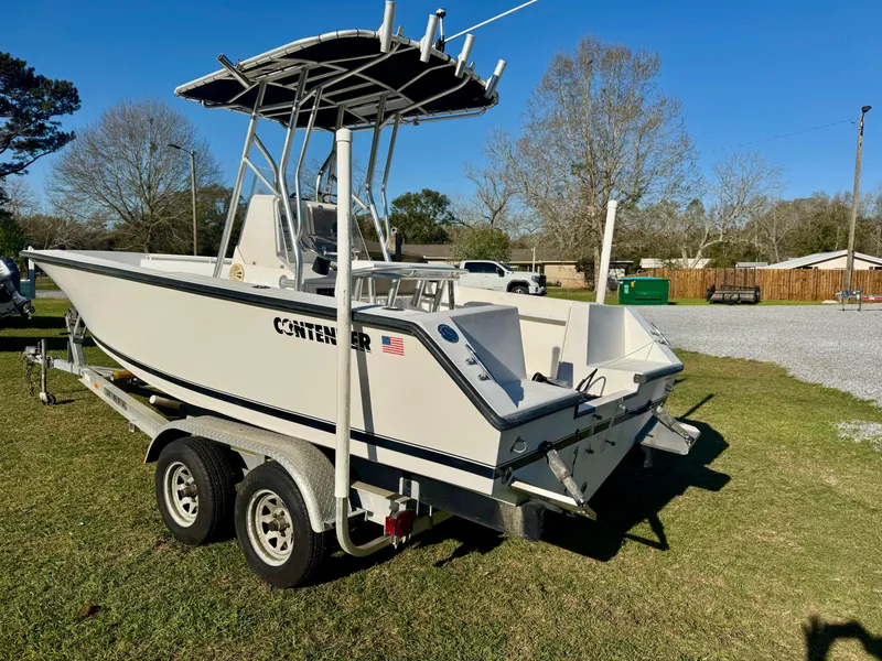 Slide: The Image of 2008 Contender 21 Open boat on trailer, parked on grass, with trees in background. - 3