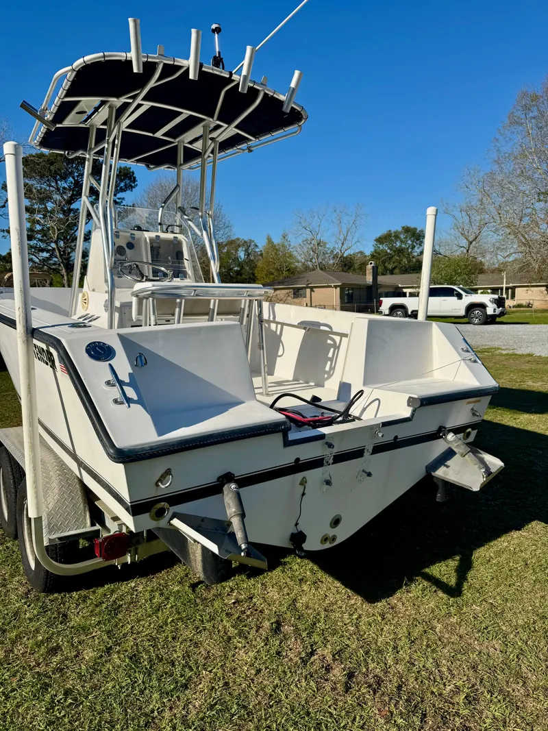 Slide: The Image of 2008 Contender 21 Open boat on grass, featuring a T-top and dual outboard mounts. - 4