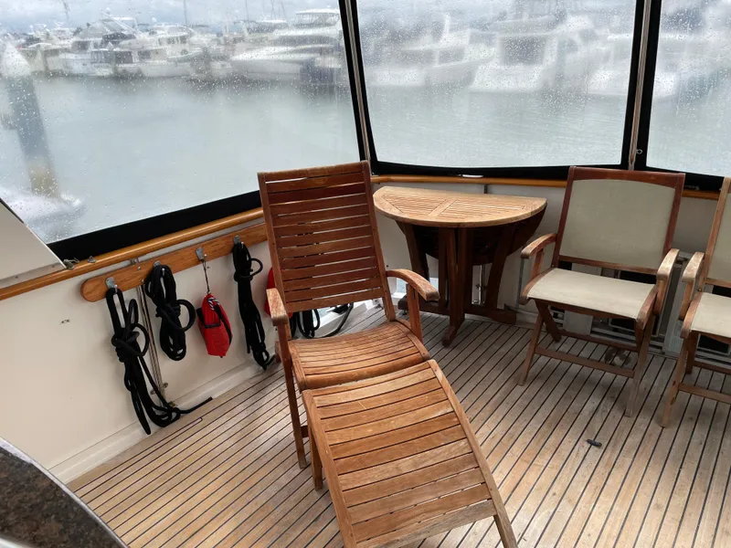 Slide: The Image of 1987 Lien Hwa 47' yacht sundeck with wooden chairs and table, overlooking marina. - 17