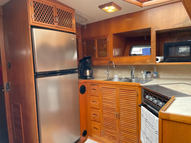 Slide: The Image of 1987 Lien Hwa 47' yacht kitchen with wood cabinetry, stainless fridge, and appliances. - 30
