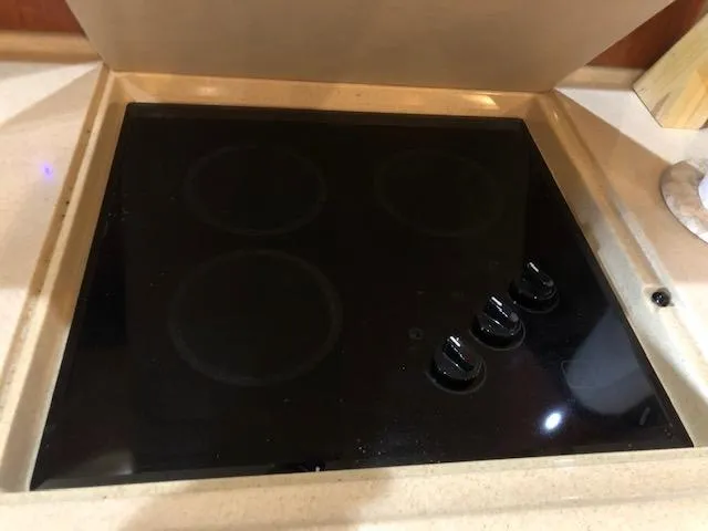 Slide: The Image of Stovetop on 2001 Sea Ray 410 Sundancer yacht, featuring three burners and control knobs. - 10