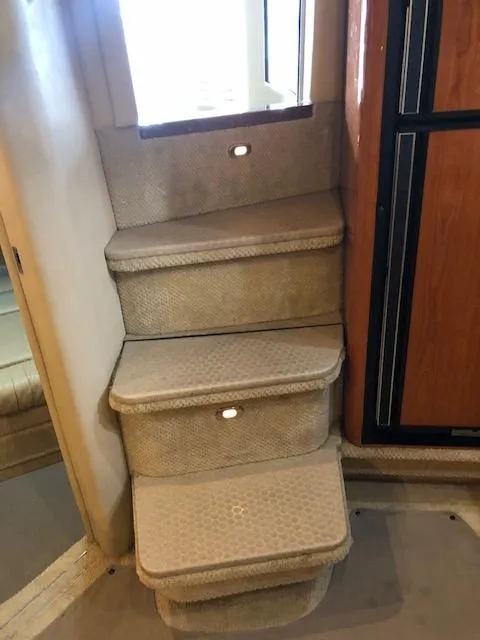 Slide: The Image of Interior stairs of 2001 Sea Ray 410 Sundancer yacht, featuring carpeted steps and ambient lighting. - 11