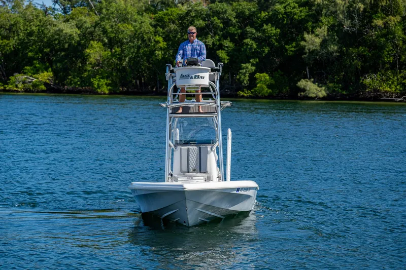Slide: The Image of 2023 Lake & Bay Backwater boat cruising on a serene lake with lush green trees. - 29