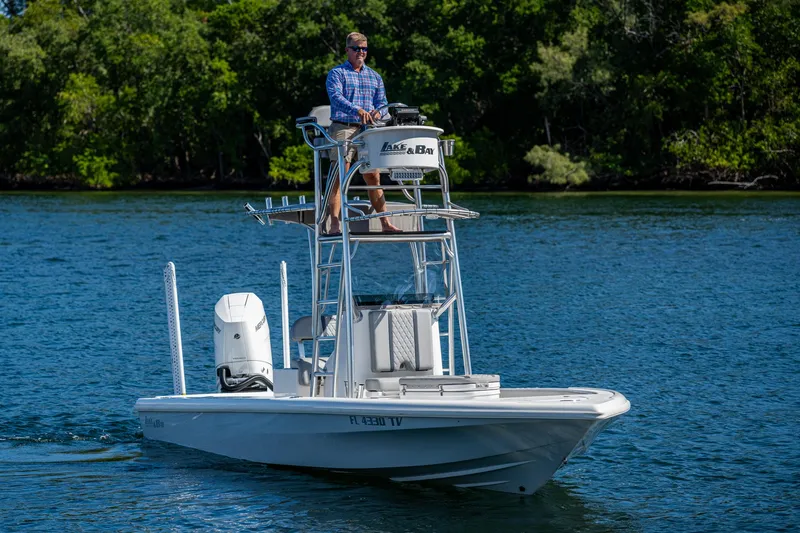 Slide: The Image of 2023 Lake & Bay Backwater boat on water, man steering, lush green background. - 3