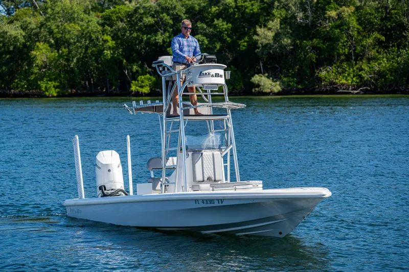 Slide: The Image of 2023 Lake & Bay Backwater boat on a calm lake with a person steering. - 30