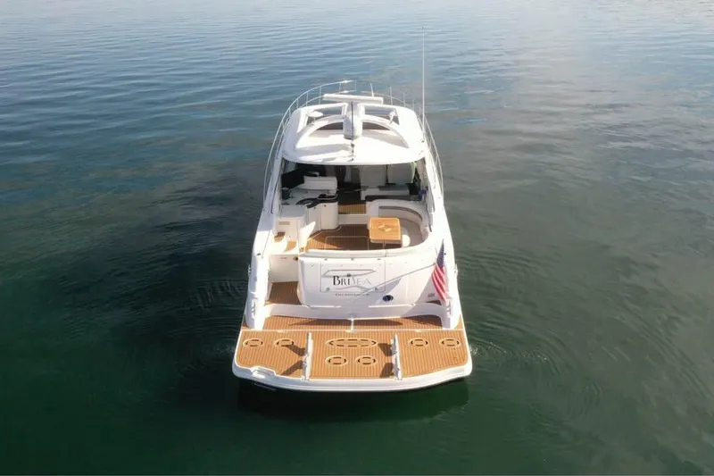 Slide: The Image of 2012 Sea Ray 500 Sundancer yacht on calm water, rear view with American flag. - 1