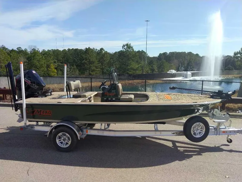 The Image of 2025 Mako 18 Pro Skiff Backwater Edition on trailer near a pond with fountain. - 0