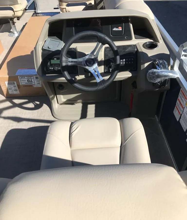 Slide: The Image of 2025 Sun Tracker Fishin' Barge 20 DLX boat interior with steering wheel and beige seating. - 4