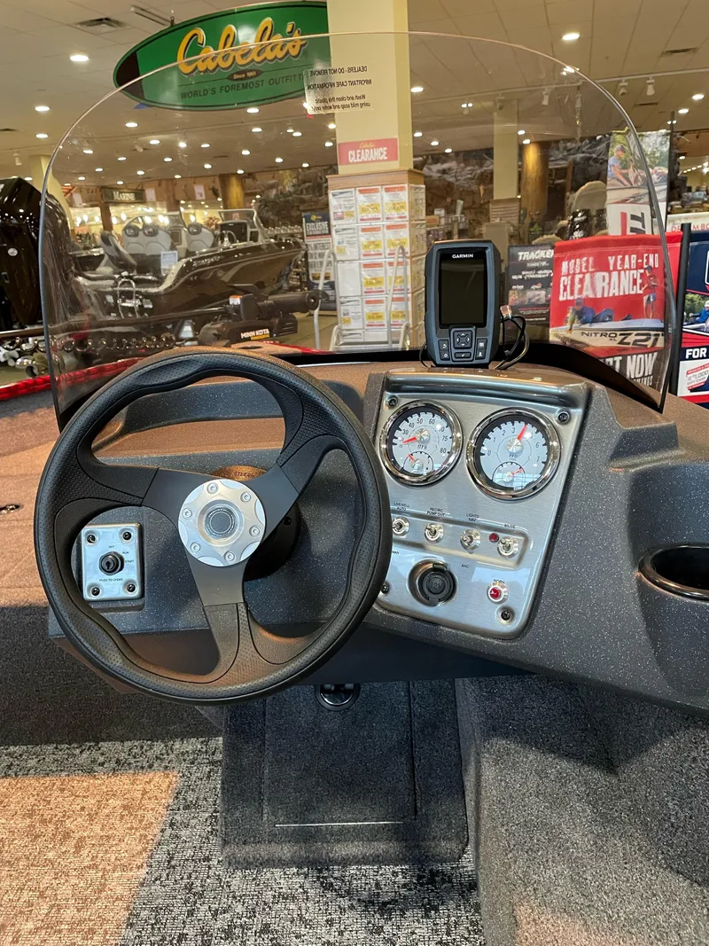 Slide: The Image of 2025 Tracker Pro Guide V-16 SC boat dashboard with steering wheel and gauges at Cabela's store. - 4
